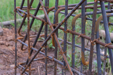 A close-up view of a rust-textured steel rebar frame used for house foundation construction, tightly tied with wire to form a strong structural grid.