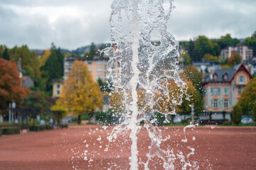 Close-up of a jet of water and splashes of a fountain in town public park, selective focus
