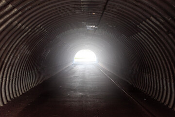 Fototapeta premium dark, corrugated metal tunnel leading to a bright light