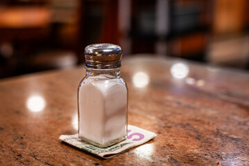 Close up of a diner salt shaker with the money tip underneath