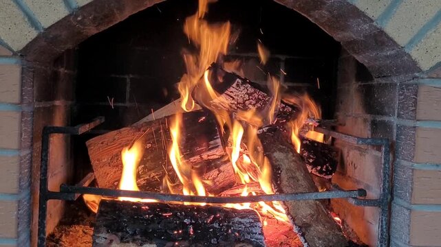 Hot fireplace full of wooden logs burning, closeup