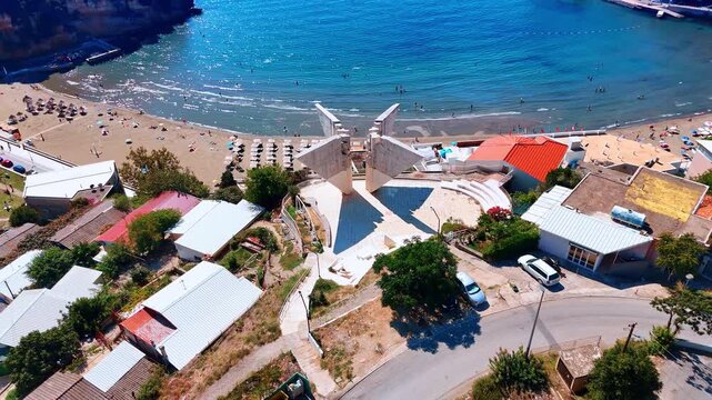 Distancing from the monument on the shore of the sea in Ulcinj, Montenegro. Rocky coast of the Adriatic Sea on sunny day from drone.