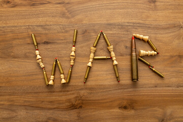 The word WAR is arranged from blank cartridges and chess pieces on a wood surface, creating a symbolic visual message about conflict, strategy and global tension.