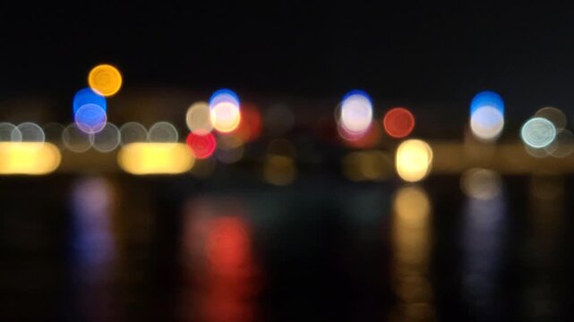 Defocused city traffic lights at night with cars passing by