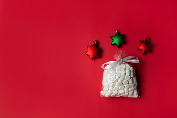 Marshmallows on red background with red and green star shaped Christmas ornaments
