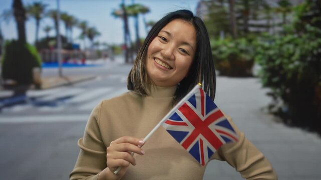 Woman smiling holding british flag on a sunny street showcasing a vibrant city atmosphere with palm trees in the background suggesting a multicultural outdoor setting.