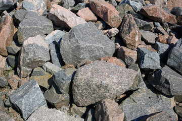 Varied collection of rocks and stones in natural setting with sunlight highlighting textures and colors, background