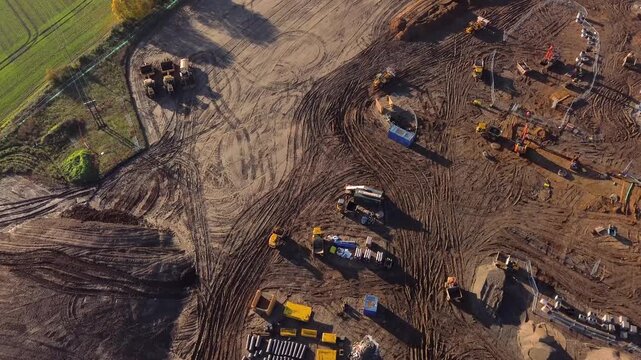 Aerial drone video of a large housing construction site with machinery, foundations, and materials being prepared for new residential development. 