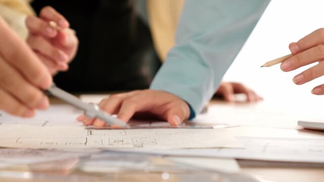 Video of architects or smart engineers use measurement tool, divider and pencil hand writing detail on blueprint for construction accuracy at architectural office. Focus on hand. Closeup. Delineation.
