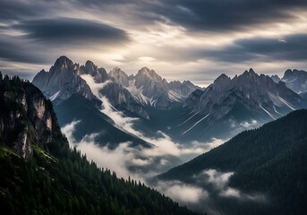 Dramatic storm clouds gather over jagged mountain peaks shrouded in mist and fog during sunrise