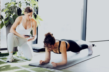 A fitness trainer is coaching a girl in the gym, guiding her and explaining proper form during exercises.
