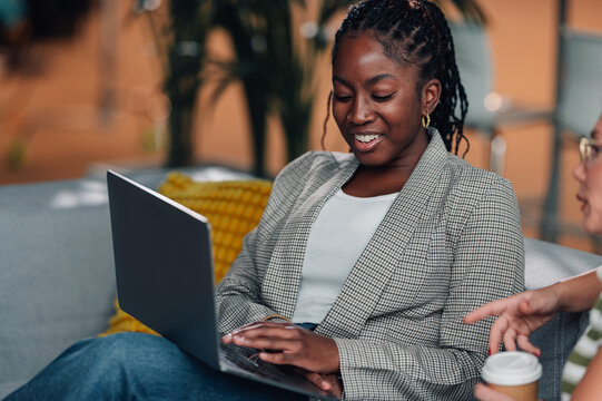 Black woman collaborating colleague using laptop computer - Powered by Adobe