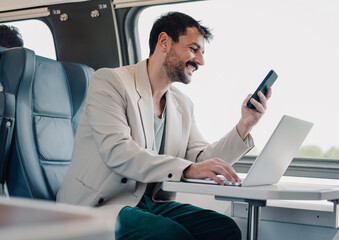Man commuting on train using laptop and phone