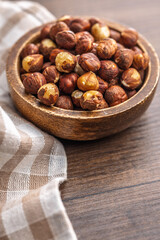 Peeled hazelnut kernels in bowl on wooden table.