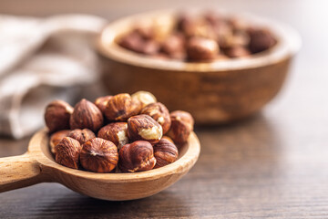 Peeled hazelnut kernels on spoon on wooden table.