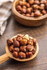 Peeled hazelnut kernels on spoon on wooden table.