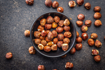 Peeled hazelnut kernels in bowl on black table. Top view.