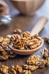 Peeled walnut kernels on wooden spoon on wooden table.