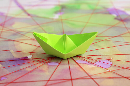 Paper boat at the intersection of several paths traced with red thread, background with watercolor stains representing variety and difficulty
