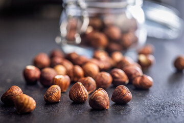 Peeled hazelnut kernels on black table.