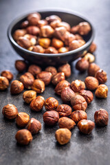 Peeled hazelnut kernels on black table.