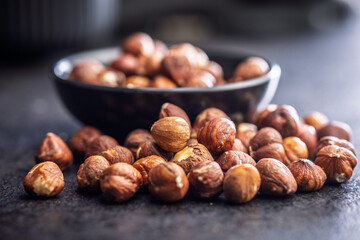 Peeled hazelnut kernels on black table.