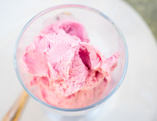 Serving of strawberry ice cream is perform in clear glass cup. Refreshing sweet dessert made with cream, sugar and strawberry puree.