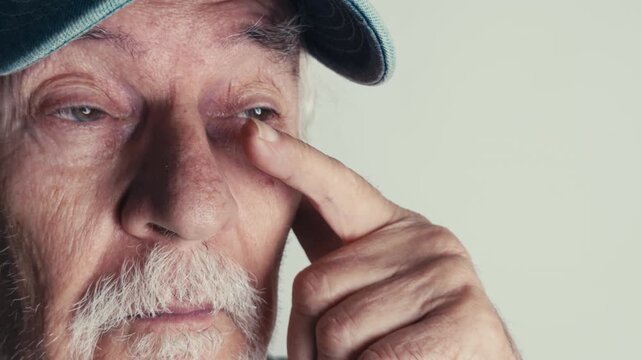 Old Man Rubs His Eyes in Discomfort