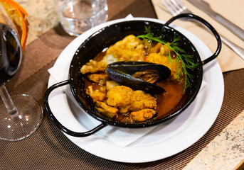 Lunch at restaurant - marinated fish cooked with seafood, decorated with sprig of dill, made perform such a casserole. Hearty meal is served with red wine and crispy baguette..