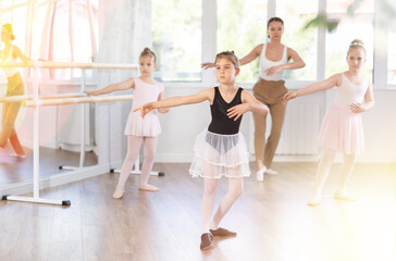 Group of girls dancers rehearsing ballet moves in studio