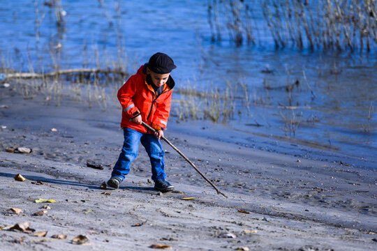 Boy playing on beach drawing with stick