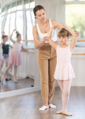 Ballet lesson for little girls - choreography teacher shows little ballerinas how to get into different poses correctly © JackF