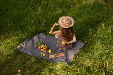 Girl checks fruit, Woman reclining on blanket inspecting orchard produce