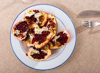 Pieces of ripe pomegranate with juicy seeds on a white plate top view
