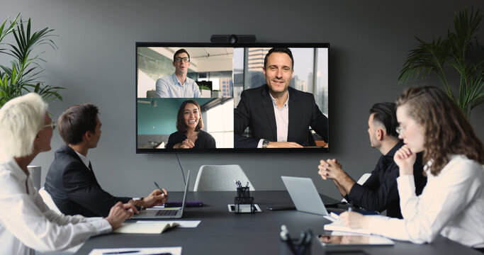 Diverse businesspeople participate in videocall, displayed on tv screen