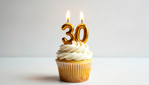 Vanilla cupcake with white cream frosting holds two lit golden number 30 candles. Sweet dessert celebrates thirtieth birthday anniversary, marking special milestone event. Perfect party treat for