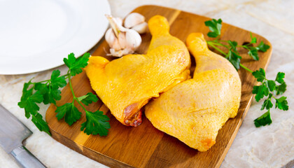 On table, ingredients for cooking dinner are prepared - two raw chicken thighs, parsley, garlic. Products set for soup, broth, top view