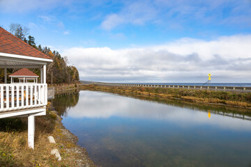 A serene rest stop in Quebec showcasing tranquil reflections, lush foliage, and an inviting gazebo under a vast sky.