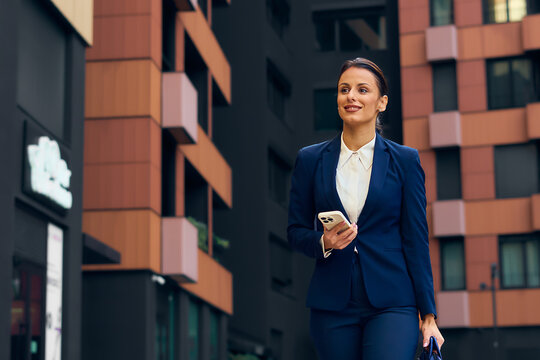 Professional Real Estate Agent in Modern Urban Cityscape Walking with Phone and Briefcase