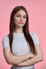 Portrait of a young beautiful student girl in a white T-shirt isolated on a pink background