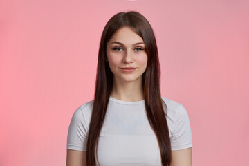 Portrait of a young beautiful student girl in a white T-shirt isolated on a pink background