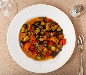 Appetizing vegetable stew in the Mediterranean style, made with natural ingredients. Stewed farm vegetables on a white plate