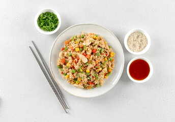 Fried rice with chicken and vegetables carrots, peppers, corn, green peas and sauce on white background. 