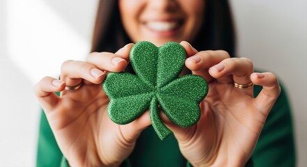 smiling person holding sparkly green shamrock symbolizing st. patrick's day celebration