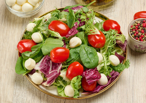 Plate of fresh salad with mixed greens, cherry tomatoes and mozzarella balls.