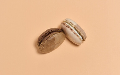 Two brown macarons on beige background, top view