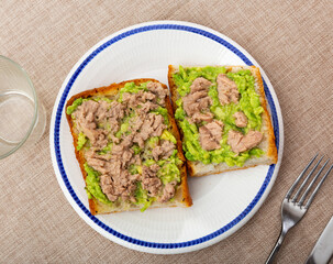 Cod liver and avocado sandwiches. Hearty snack is made using baguette and canned cod liver.