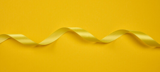 A yellow satin ribbon, curved into a wave, centered on a yellow background.