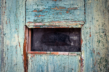 Peeling turquoise paint on weathered wooden door with narrow mail slot, distressed texture and natural patterns, high‑detail architectural background for restoration concepts - south of Portugal