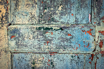 Close‑up of peeling turquoise paint on weathered wooden door panels, cracked and flaking surface forming abstract grunge texture with geometric shapes and natural patterns - south of Portugal